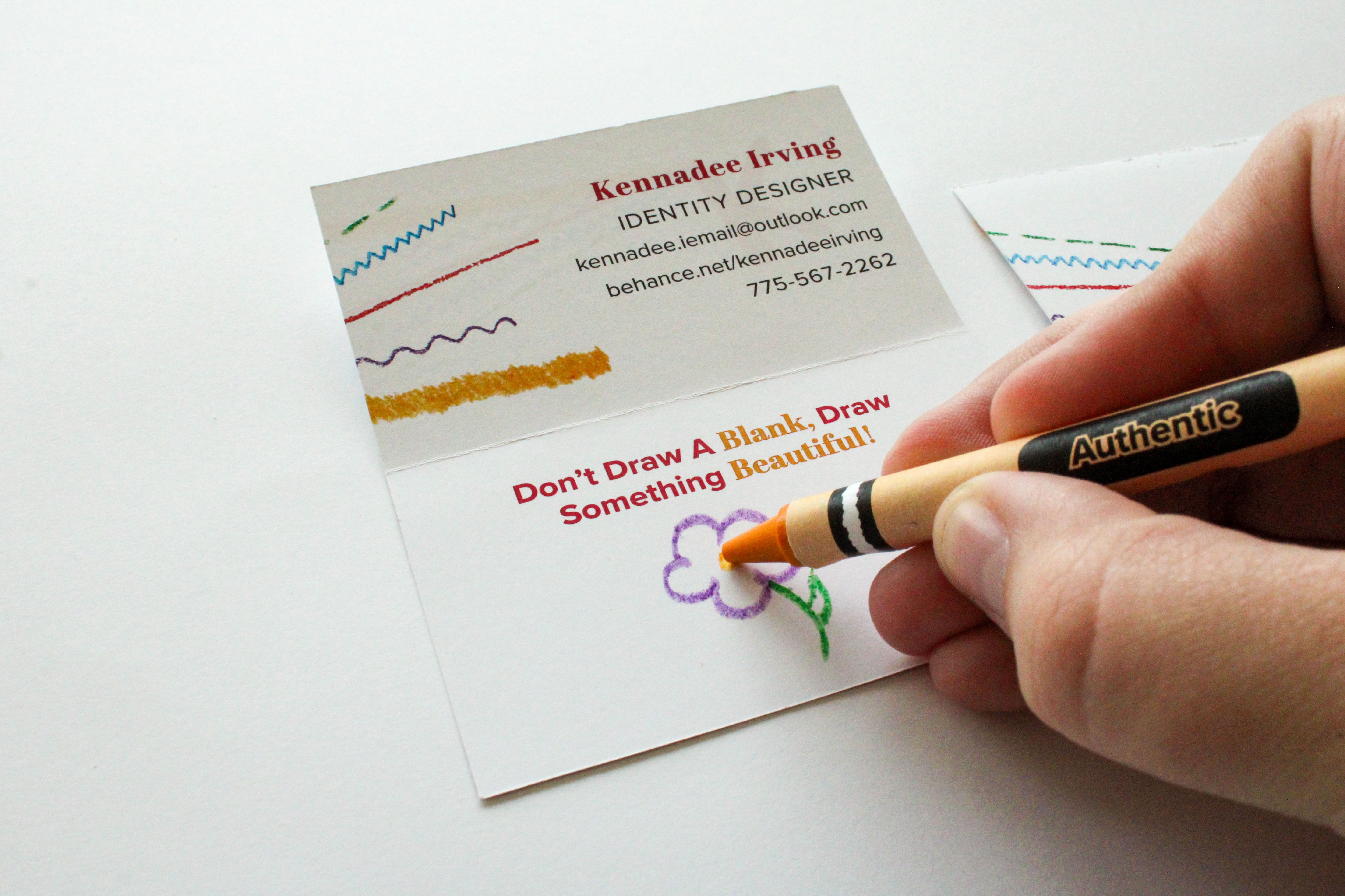 Person coloring a purple flower on a business card